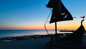 A sailboat silhouette against a sunset sky, with a bird perched on the mast.