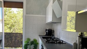 A modern kitchen with a black countertop, stainless steel appliances, and a large window overlooking a balcony. - Jaris Apartment (Vicenza)