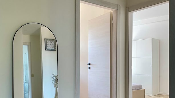 A modern bedroom with a large mirror, a bed with a white duvet, and a marble floor. - Jaris Apartment (Vicenza)