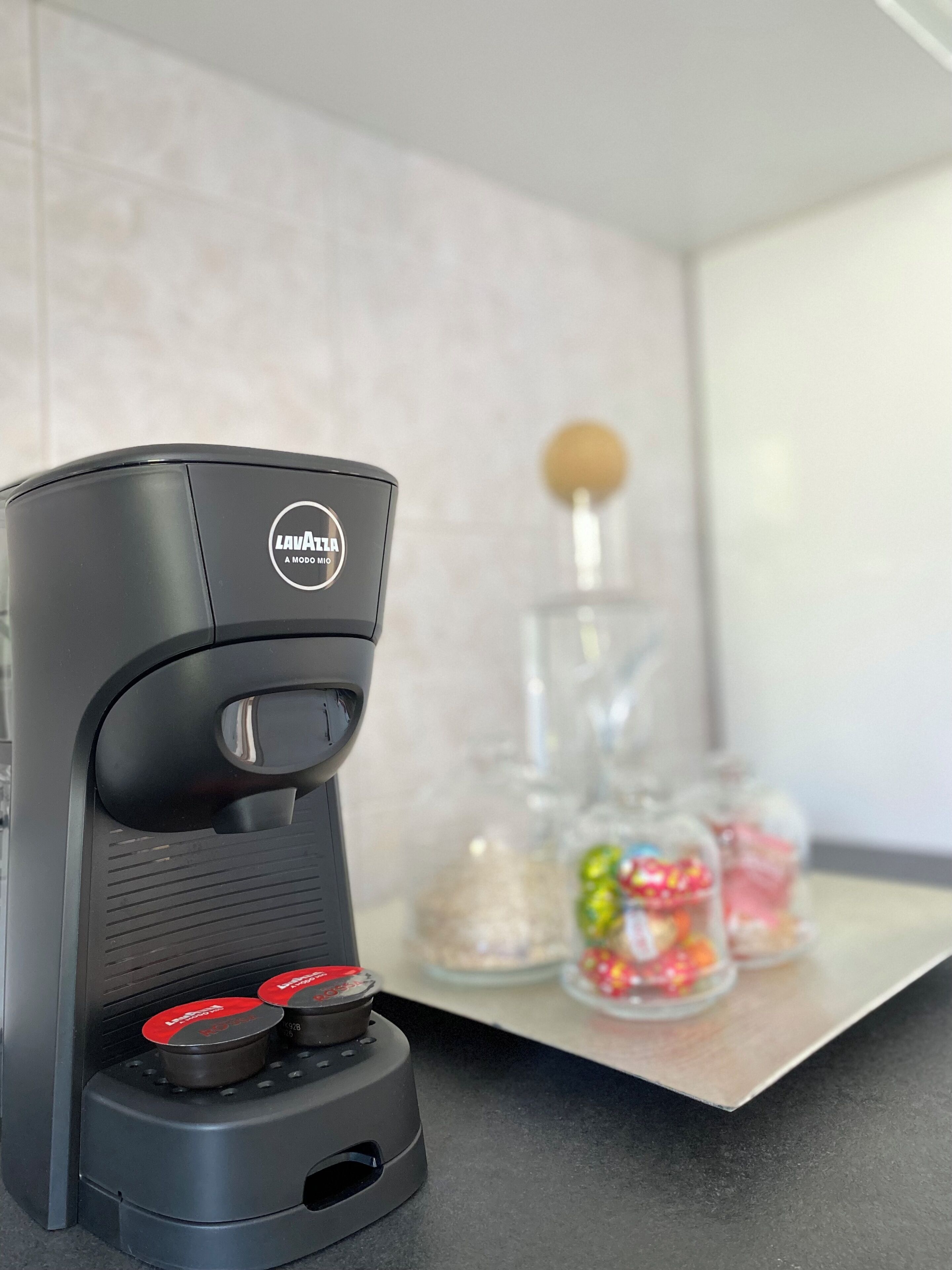 Eine schwarze Kaffeemaschine mit einem Aufkleber auf der Vorderseite, auf einer Arbeitsplatte platziert.