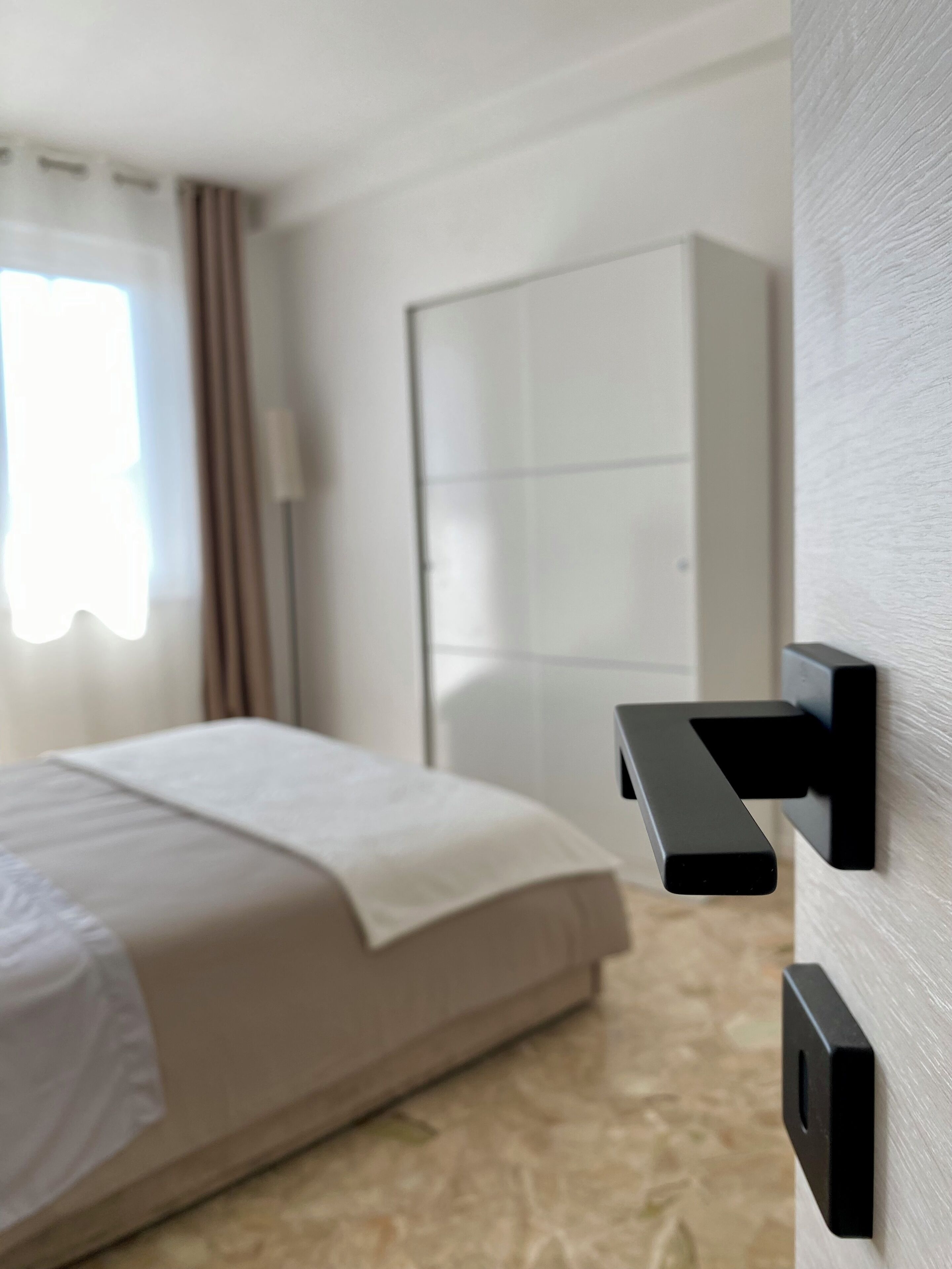A hotel room with a bed, a wardrobe, and a wall-mounted control panel.