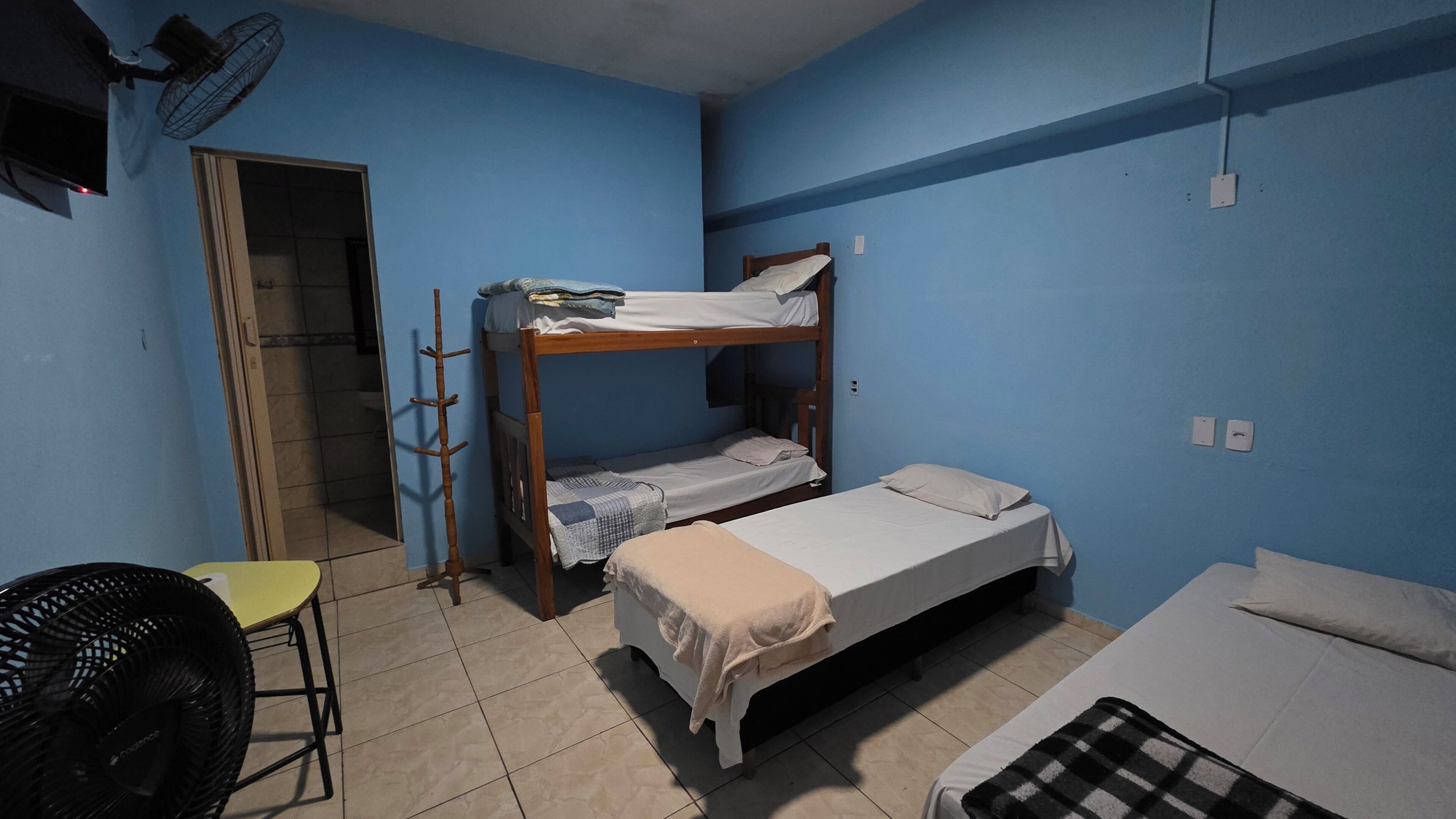Habitación tipo dormitorio con literas, una silla y un ventilador.
