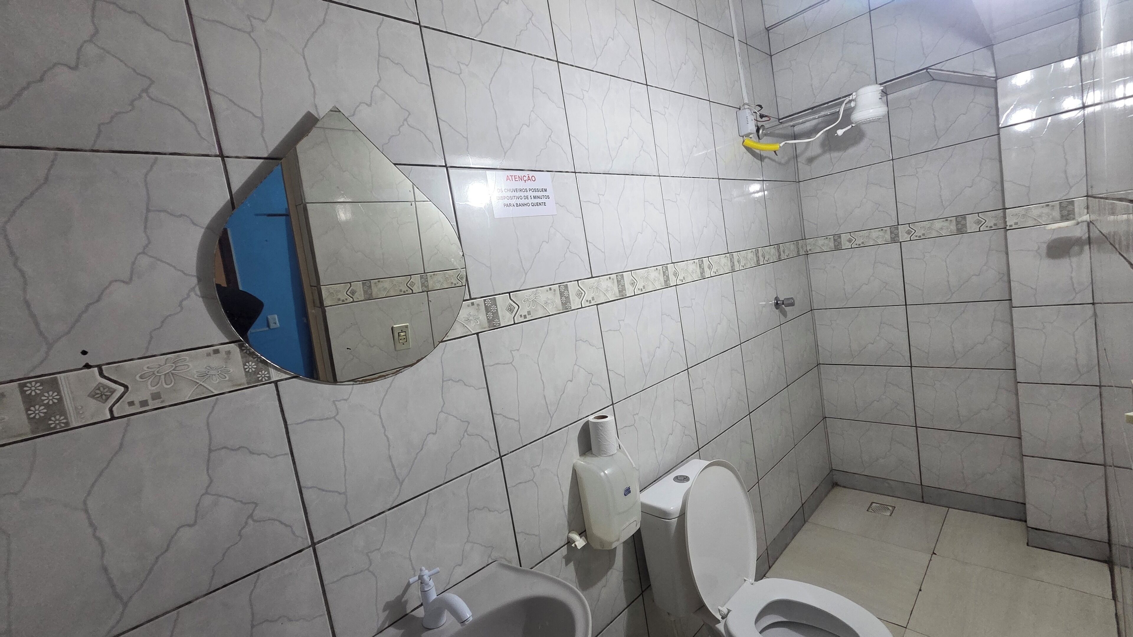 Casa de banho com sanita, secador de mãos e dispensador de papel.