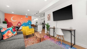 Ein modernes Wohnzimmer mit einer Couch, einem gelben Sessel, einem Couchtisch und einem an der Wand montierten Fernseher.