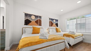 A hotel room with two beds, white bedding, and a wooden floor.