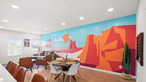A dining area with a mural, wooden flooring, and modern furniture.