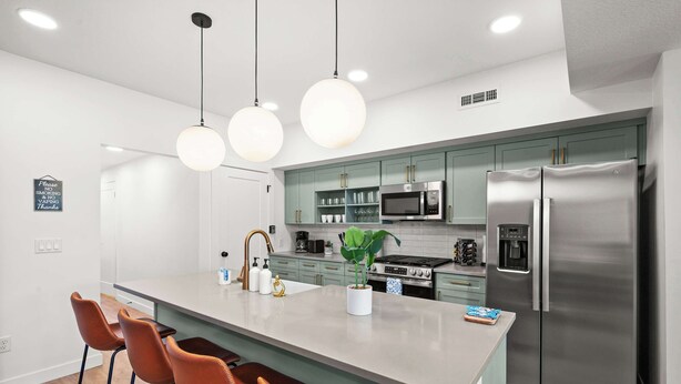 A modern kitchen with a central island, stainless steel appliances, and pendant lighting.