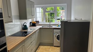 Een moderne keuken met grijze kastjes, een ingebouwde vaatwasser, een spoelbak en een raam met uitzicht op groen.