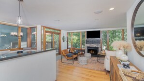 A spacious living room with a fireplace, comfortable seating, and large windows.