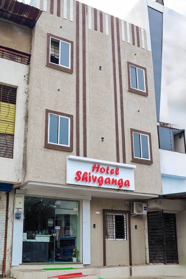 A hotel named "Hotel Shivanganga" with a signboard, multiple windows, and a glass entrance. - Hotel Shivganga (Ujjain)