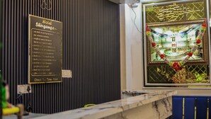 A hotel reception area with a check-out time sign, a projector, and a decorative window view. - Hotel Shivganga (Ujjain)