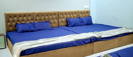 A bed with a tufted headboard, blue bedding, and a patterned throw.