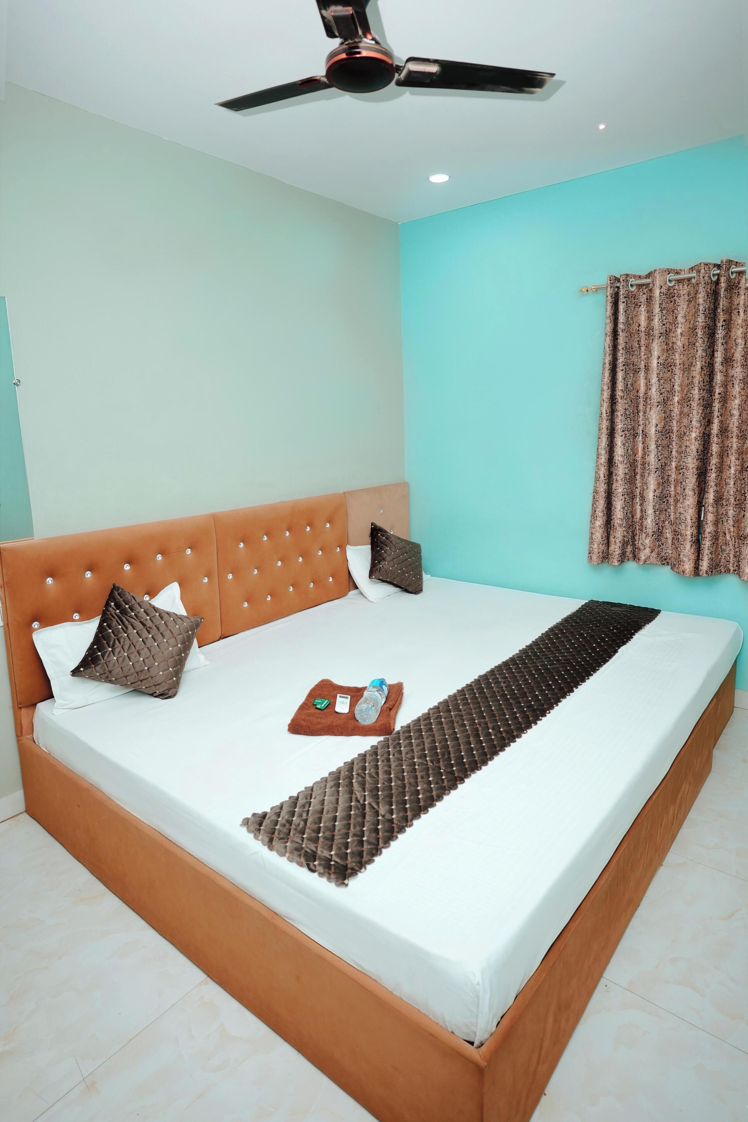 A bed with a headboard, pillows, a blanket, and a bedside table with a bottle and a tissue box.