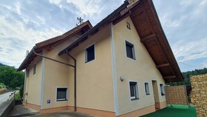 A two-story building with a sloped roof, multiple windows, and a paved entrance area. - Vacation apartment Haus-Buxbaum near Lake Wörthersee (Sankt Martin am Techelsberg)