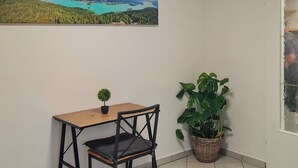 A room with a small table and chair, a potted plant, and a large landscape painting on the wall. - Vacation apartment Haus-Buxbaum near Lake Wörthersee (Sankt Martin am Techelsberg)