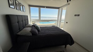 A bedroom with a large bed, a view of the ocean, and a pool. - Lagon, reef beach 414 (La Serena)