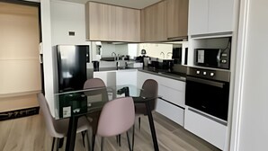 A modern kitchen with a glass dining table, two chairs, a refrigerator, a microwave, and a stove. - Lagon, reef beach 414 (La Serena)