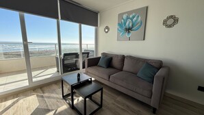A living room with a sofa, a coffee table, and a large window overlooking the beach. - Lagon, reef beach 414 (La Serena)