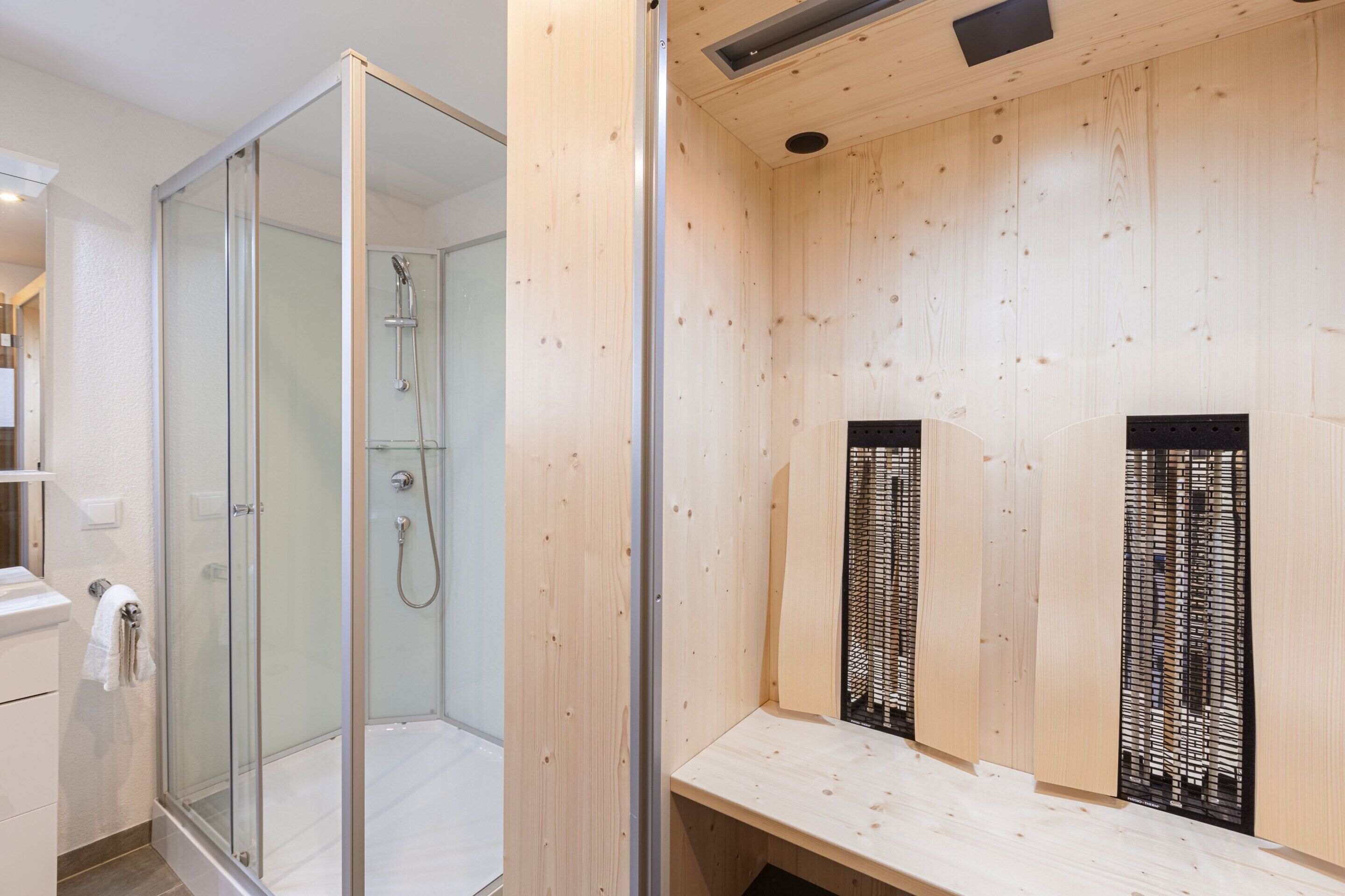 A modern bathroom with a glass-enclosed shower, wooden paneling, and a built-in bench.