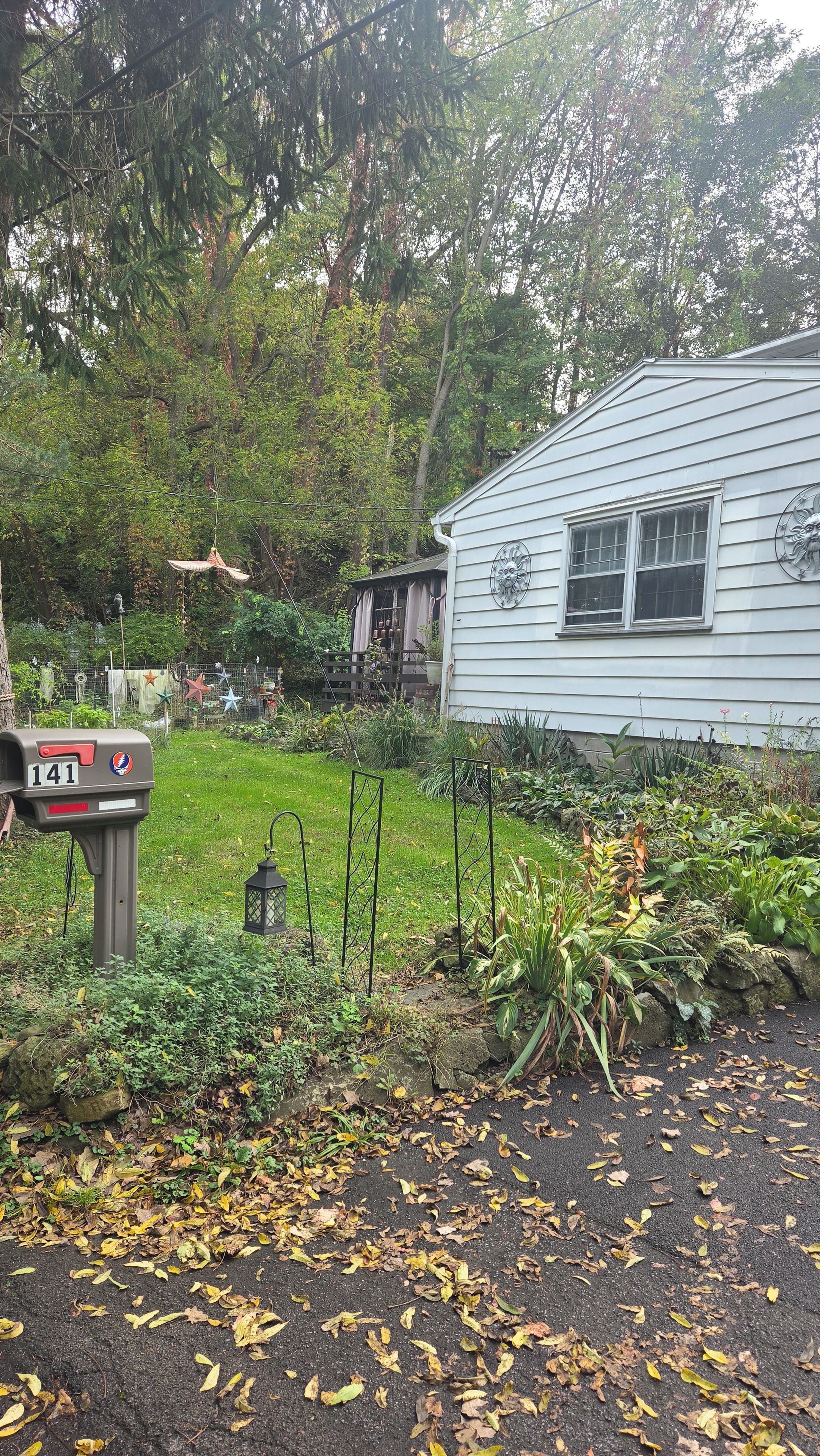 A residential property with a mailbox, a garden with various plants, and a house with a distinct window design.