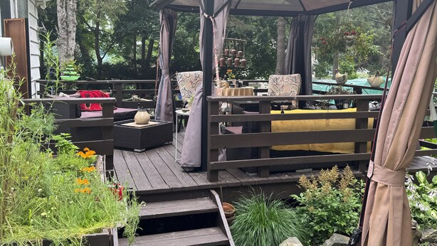 Une terrasse extérieure couverte, aménagée avec des sièges, une pergola et une variété de plantes.