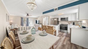 A modern kitchen with white cabinets, stainless steel appliances, and a dining area with a table set for four.