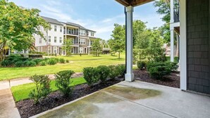 A residential building with a covered porch, a well-maintained lawn, and a clear sky. - One Tree Hill Townhouse - Downtown w/Garage! (Wilmington)