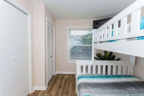 A bedroom with a bunk bed, a closet, and a window with blinds.