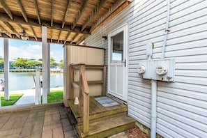 A covered porch with a wooden bench, a welcome mat, and a view of a lake.