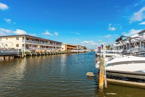 Un puerto deportivo con barcos amarrados, un edificio con balcones y un cielo azul despejado.