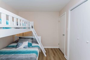A bunk bed with a ladder, a door, and a wooden floor.