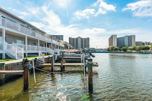 A waterfront hotel with a dock, a boat, and a cityscape in the background.