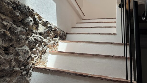 A staircase with white walls and wooden steps, leading upwards.