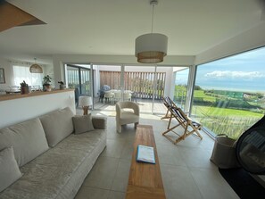 Una sala de estar moderna con un sofá, una mesa de centro y vistas a un balcón con mobiliario exterior.
