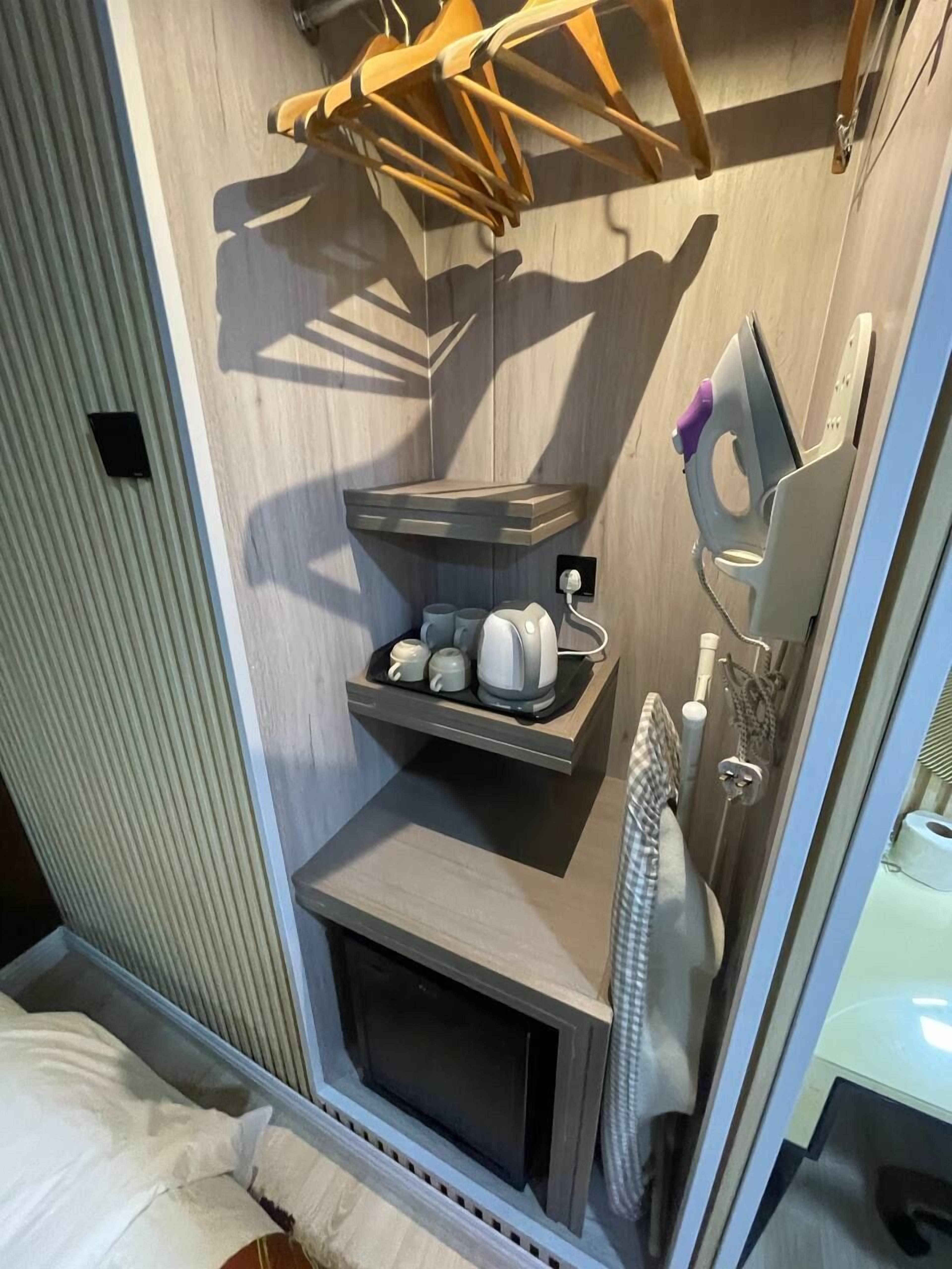 Un baño pequeño con tocador de madera, un perchero y un estante con artículos de aseo.