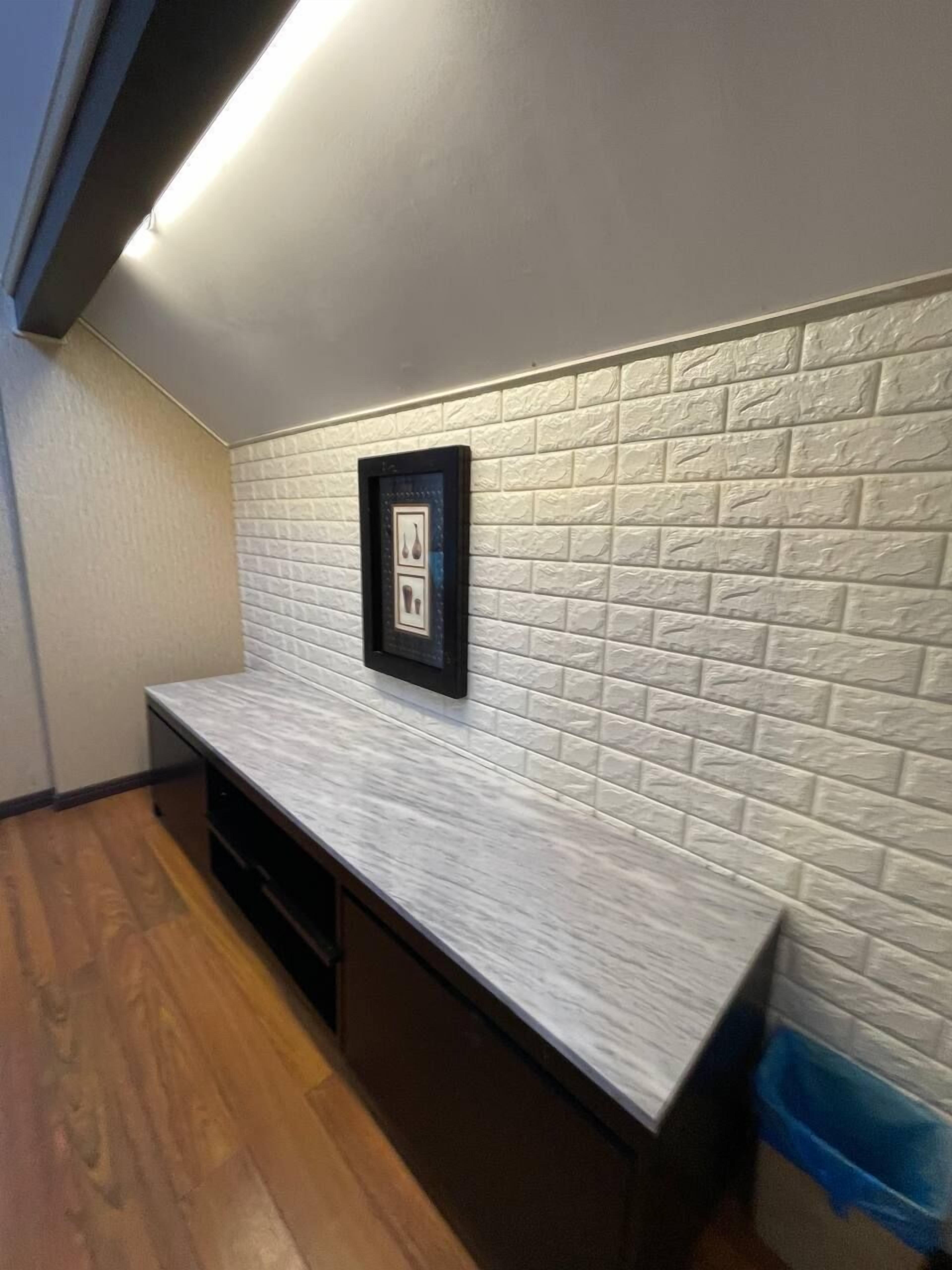 A kitchen with a white textured backsplash, a framed picture, and a wooden countertop.