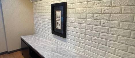 A kitchen with a white textured backsplash, a framed picture, and a wooden countertop.