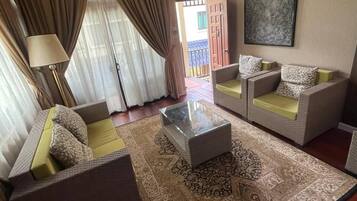 Un soggiorno con ventilatore a soffitto, due divani, un tavolino da caffè e un tappeto decorato.