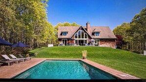 A large house with a swimming pool, surrounded by trees and a well-maintained lawn. - Sensational & Sophisticated 5 Bedroom Home in East Hampton (East Hampton)