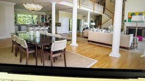 A spacious living area with a dining table, chairs, a sofa, and a staircase leading to an upper level. - Sensational & Sophisticated 5 Bedroom Home in East Hampton (East Hampton)