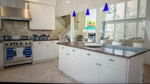 A spacious kitchen with white cabinets, a large island, and a stainless steel range hood. - Sensational & Sophisticated 5 Bedroom Home in East Hampton (East Hampton)