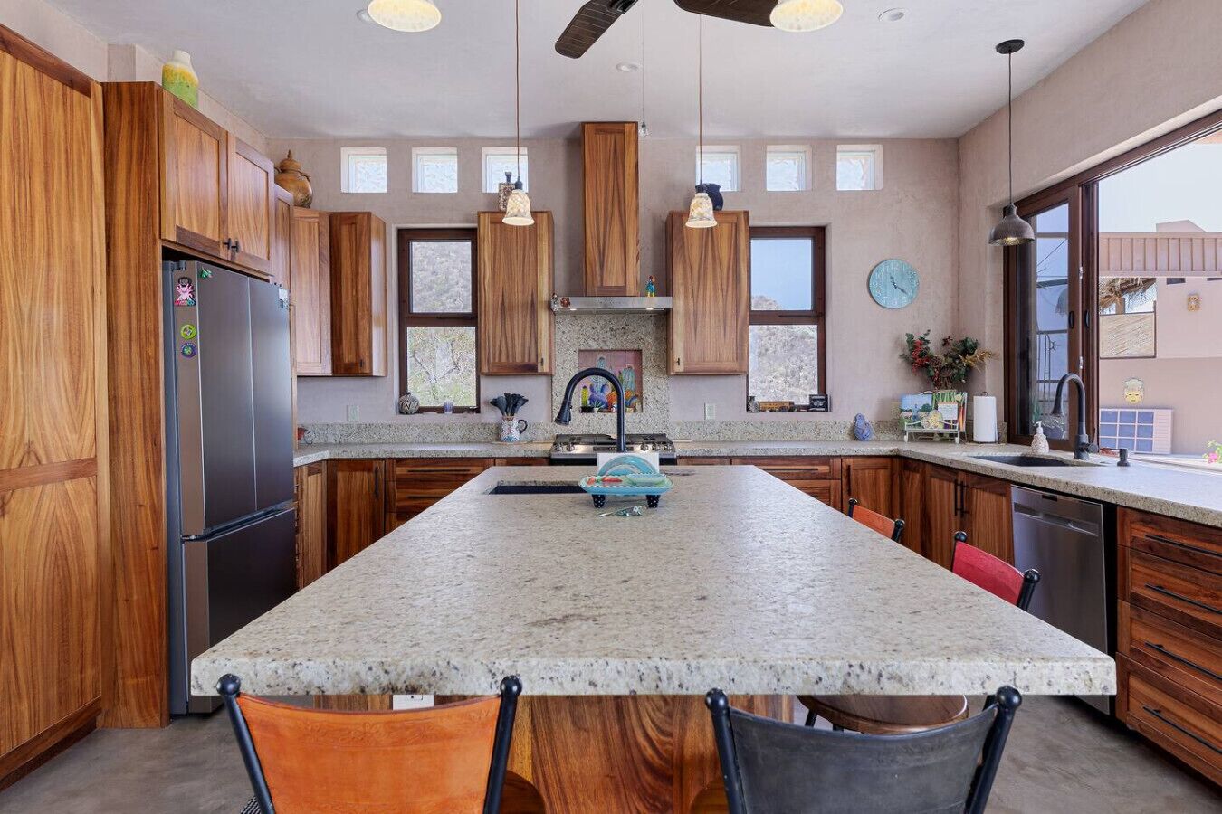 A spacious kitchen with a large island, wooden cabinets, and a modern faucet.