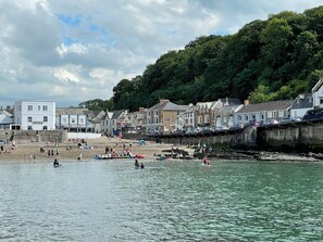 A coastal town with a sandy beach, boats, and people engaging in water activities. - Seaside Apartments (Ilfracombe)