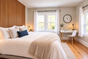 A bedroom with a large bed, a desk, and a clock on the wall. - Jennifer's Elegant & Cozy Broadway Walkable Stay (Providence)