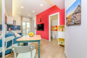 A modern living room with a blue sofa, a wooden table with a bowl of fruit, and a red accent wall. - Domus Sirenum (Sorrento)