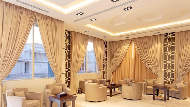 Ein geräumiges Wohnzimmer mit beigefarbenen Sofas, einem Couchtisch und großen Fenstern mit Vorhängen.
