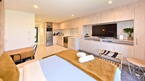 Una habitación de hotel moderna con cama, escritorio, kitchenette y televisor.