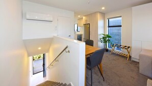A modern apartment with a staircase, a dining area, a kitchen, and a large window. - Cosy CBD Studio Apartment 12 (Christchurch)