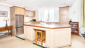 A modern kitchen with a central island, built-in appliances, and a view to the outside.