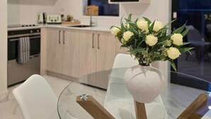 Una cucina moderna con mobili in legno, un tavolo da pranzo in vetro e un vaso di fiori.